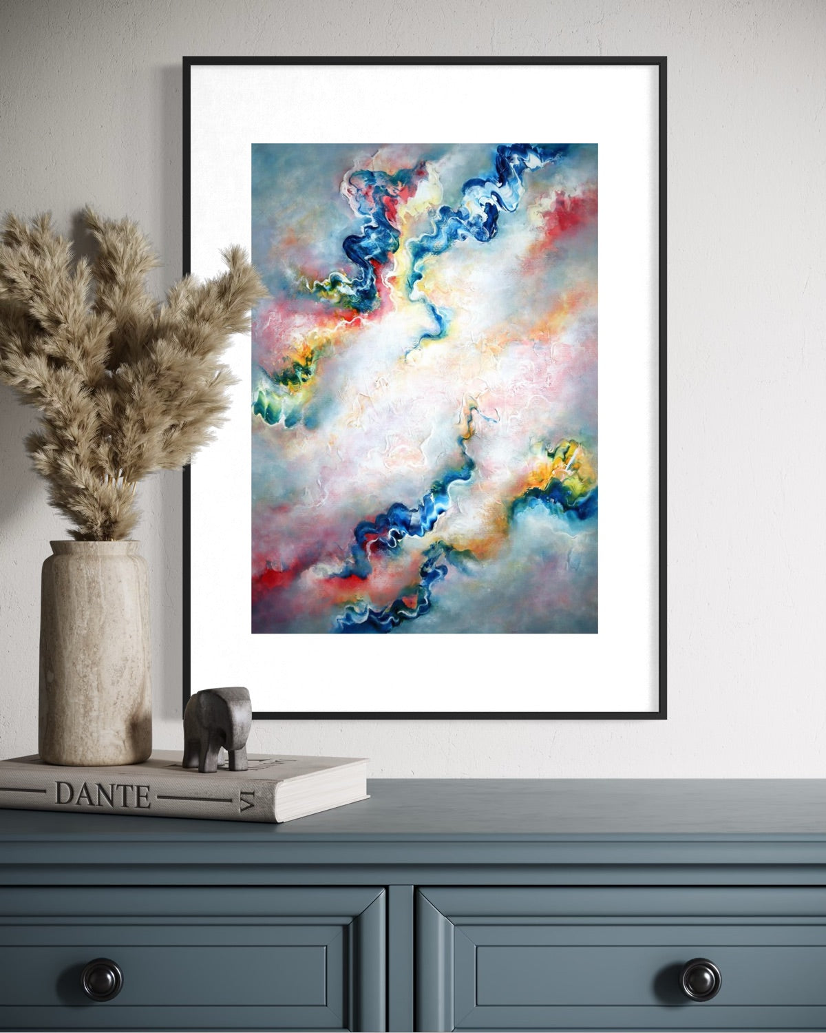 Framed grey abstract wall art print on a wall above a blue cabinet with decorative items
